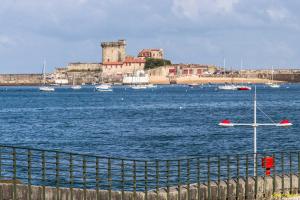 un grupo de barcos en un gran cuerpo de agua con un castillo en Entre Terre & Mer, en Ciboure