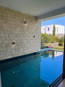 a swimming pool in a house with a stone wall at Akamas Turtle Beach №2 in Neo Chorio