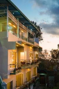 バニュワンギにあるBella Vista Premium Homestayのバルコニー付きの建物で、夕日を背景に眺めることができます。