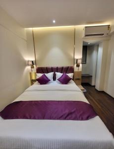 a bedroom with a large bed with purple pillows at Vishal Hall in Mumbai
