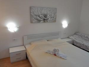 a bedroom with a white bed with a flower painting on the wall at Apartments Josip 2830 in Rab