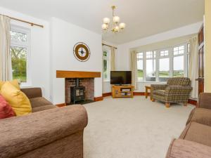 a living room with a fireplace and a tv at Pillhead Cottage in Westleigh