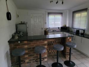 cocina con encimera y taburetes en Tally-Grey Cottage, en Albert Falls