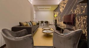 a living room with a couch and a tv and chairs at Abando Suites by Next Stop Bilbao in Bilbao