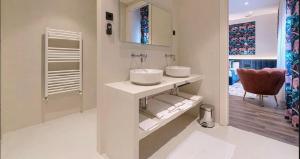 a white bathroom with two sinks and a red chair at Abando Suites by Next Stop Bilbao in Bilbao