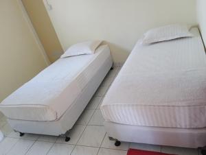 2 aparte bedden in een kamer met een tegelvloer bij Balqis Homestay Syariah II Pasar Aur Kuning in Bukittinggi