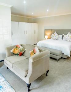 a bedroom with a bed and a couch and a chair at The Midlands Hotel in Pietermaritzburg