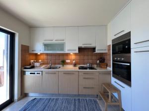 a kitchen with white cabinets and a large window at Casa Parreira Raposeira, Algarve in Raposeira