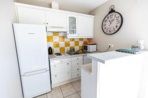 una cocina con armarios blancos y un reloj en la pared en La Minoterie, en Tessy-sur-Vire