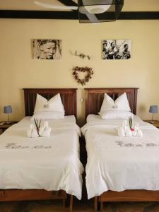 2 camas con sábanas blancas en una habitación en Fiume Lodge CC, en Groutfontein