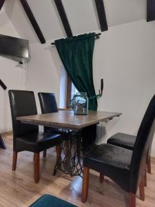 a dining room table with black chairs and a green curtain at Apartament Krawcownia in Świebodzin