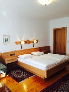 - une chambre avec un grand lit en bois et des draps blancs dans l'établissement Pension Buch, Bed and Breakfast, à Eberau