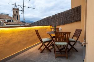 ビックにあるNiu del Solのテーブルと椅子、黄色い壁のバルコニー