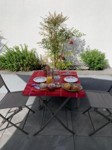 a red table with plates of food on a patio at Maison M, chambre privée accès jardin piscine et jacuzzi près de La Rochelle in La Rochelle