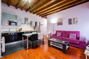 トレドにあるApartamento con patio junto a la Catedral by Toledo APの紫色のソファ付きのリビングルーム、キッチンが備わります。