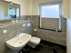 a bathroom with a sink and a toilet and a window at Ferienwohnung *Haus Ose* in Wittdün +8 photos