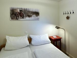 a bedroom with a bed with white pillows and a lamp at Ferienwohnung *Haus Ose* in Wittdün