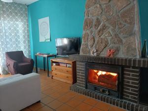 ein Wohnzimmer mit einem Kamin und einem TV in der Unterkunft Casa Rural con Piscina y AA en Sierra Oeste de Madrid in Pelayos de la Presa