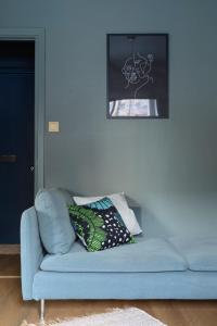 a blue couch with two pillows in a living room at Hip studio near Central Park and City Center in Helsinki