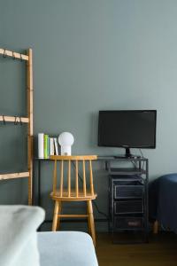 um quarto com uma televisão e uma cadeira de madeira em Hip studio near Central Park and City Center em Helsinque