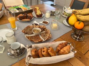 un tavolo con colazione a base di prodotti da forno, banane e arance di Chambre d’hôte de Charme avec Piscine privative a Eyguières