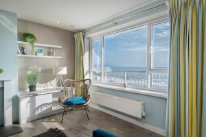 Cette chambre dispose d'une chaise et d'une fenêtre avec vue. dans l'établissement Dolphins Apartment - Spectacular Sea Views, à Saundersfoot