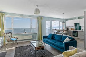 Il comprend un salon avec un canapé bleu et une cuisine. dans l'établissement Dolphins Apartment - Spectacular Sea Views, à Saundersfoot