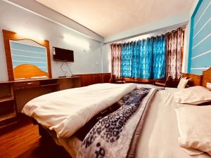 a bedroom with two twin beds and a television at Hotel D Kanchan Manali in Manāli