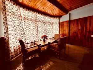 um quarto com uma mesa e cadeiras e uma janela em Hotel D Kanchan Manali em Manali