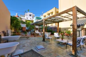 patio ze stołami i krzesłami oraz dużym drzewem w obiekcie Villa Herencia Hotel w mieście San Juan