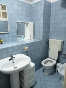 a blue tiled bathroom with a sink and a toilet at Cala Maluk in Lampedusa