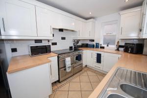 una cocina con armarios blancos y fregadero en EmmaDale Bridington Town Centre Sleeps 10, en Bridlington