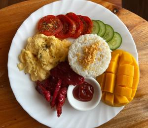 a plate of food with eggs and vegetables and fruit at Villa Alessandra Homestay in Moalboal