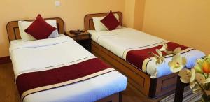 two beds in a hotel room with red and white sheets at Hotel Premium in Kathmandu