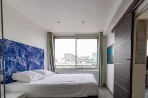 sypialnia z łóżkiem z niebieskim zagłówkiem i oknem w obiekcie Le Suffren-Eiffel Appartement w Paryżu