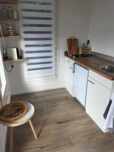 a kitchen with white cabinets and a wooden floor at Havenkantoortje in Woudsend