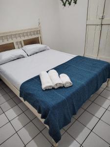 a bed with two white towels on a blue blanket at Casa Porto de Pedras_Patacho_Milagres in Pôrto de Pedras
