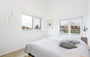 a white bedroom with a bed and two windows at Cozy Home In Lembruch-dmmer See With Sauna in Lembruch