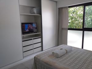 a white bedroom with a bed with a television and a window at Mirador La Viña in Salta
