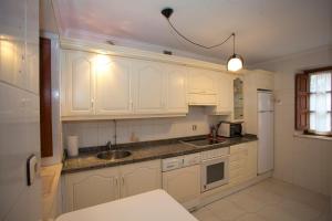 una cocina con armarios blancos y fregadero en Casa El Campón -Arriondas 22A01 en Collía