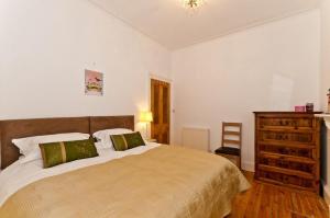 a bedroom with a large bed and a wooden dresser at Blue Seas in North Berwick