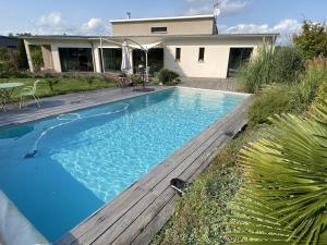 una piscina con terraza de madera junto a una casa en Villa contemporaine avec piscine sur 4000 m2 à Rodez 9 personnes, en Onet le Château