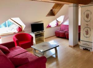 salon z czerwoną kanapą i telewizorem w obiekcie Appartamenti panoramici direttamente sulle piste da sci - Golf Hotel Carezza - Nova Levante w mieście Bolzano