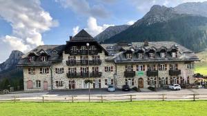 duży kamienny budynek z górami w tle w obiekcie Appartamenti panoramici direttamente sulle piste da sci - Golf Hotel Carezza - Nova Levante w mieście Bolzano