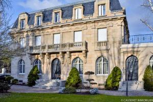 un gran edificio de piedra con árboles delante de él en Villa Bonnabel, en Nancy