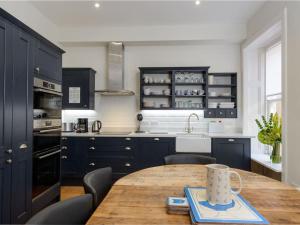 uma cozinha com uma mesa de madeira e armários azuis em By The Sea em North Berwick