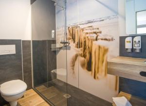 a bathroom with a toilet and a glass shower at Stadthotel-Garni Smutje in Norden