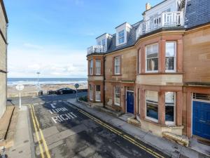 an empty street in front of a building with the ocean at By The Sea in North Berwick