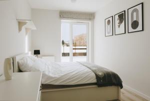 a white bedroom with a bed and a window at Apartament Symfonia Mozarta in Warka