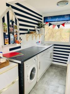 a kitchen with a sink and a washing machine at “BLISS ON THE BAY ” chalet in Sandown Bay Holiday Park in Sandown